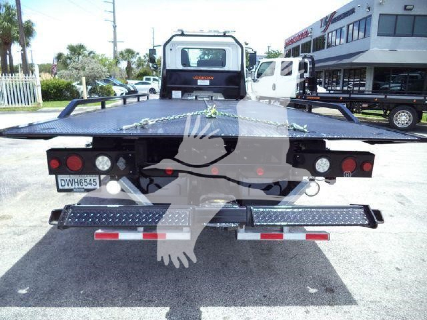 Rear view of a Hino rollback tow truck demonstrating a flatbed with dual rear taillights and safety lights.