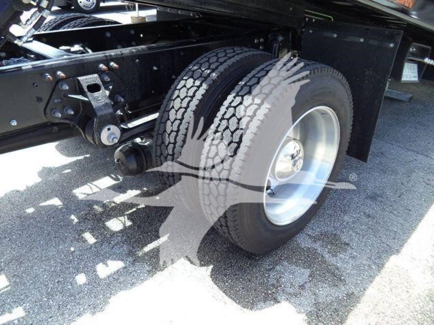 Truck rear wheel and chassis in a rollback configuration showing dual tires and suspension components