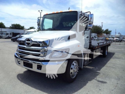 Hino L6 rollback truck in white with chrome grille and flatbed, front three-quarter view showing cab and cargo bed.