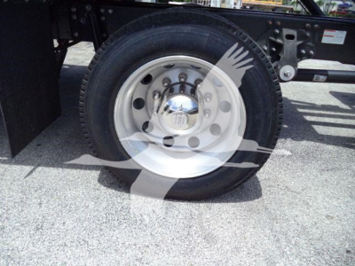Truck wheel and tire assembly on a Hino L6 rollback truck showing polished steel rim, lug nuts, and hub cap.