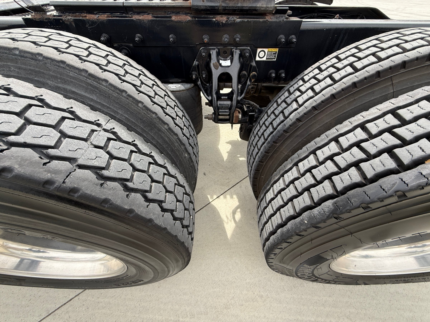 Dual rear wheels and fifth-wheel/landing gear area of a Peterbilt 579 conventional daycab showing tandem axle tires and chassis components.
