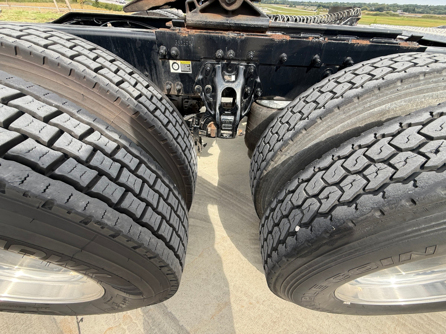 Peterbilt 579 chassis view showing dual rear axles with tires and suspension components, mid-section framing and a warning label on the frame.