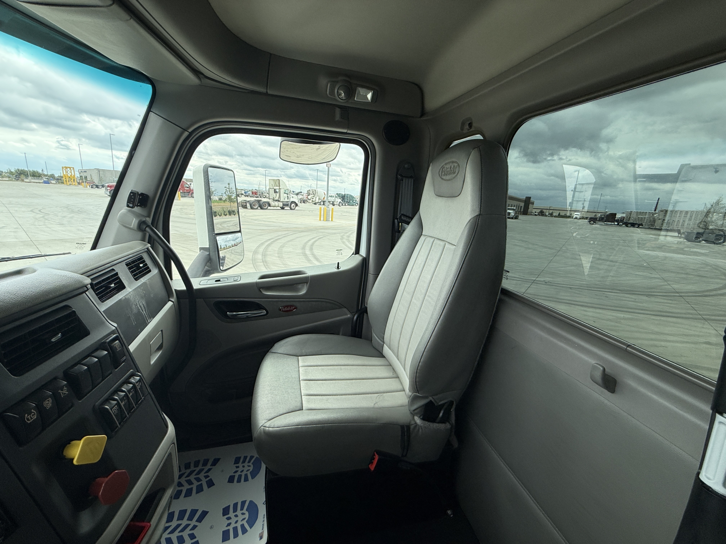 Cab interior of a 2020 Peterbilt 579 truck showing steering wheel, dashboard, and driver seat with light gray upholstery.