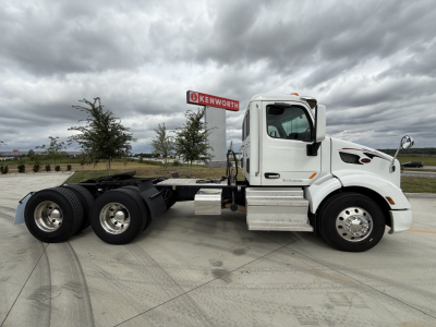 Peterbilt 579 tractor cab side view showing chassis and rear axles with stock number 0632204 on sign in background.