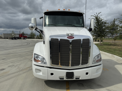 Peterbilt 579 daycab front view showing large black grille, white cab, dual chrome mirrors, and headlight assemblies.