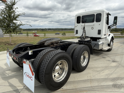 Peterbilt 579 tractor rear view showing dual rear axles and white sleeper cab with fuel tanks and wheels.