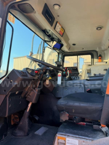 Cab interior of a Mack MRU613 truck showing steering wheel, dashboard, and driver seat with controls visible.