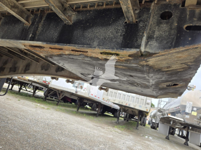 Trailer undercarriage view showing underside of flatbed with metal frame and support beams.