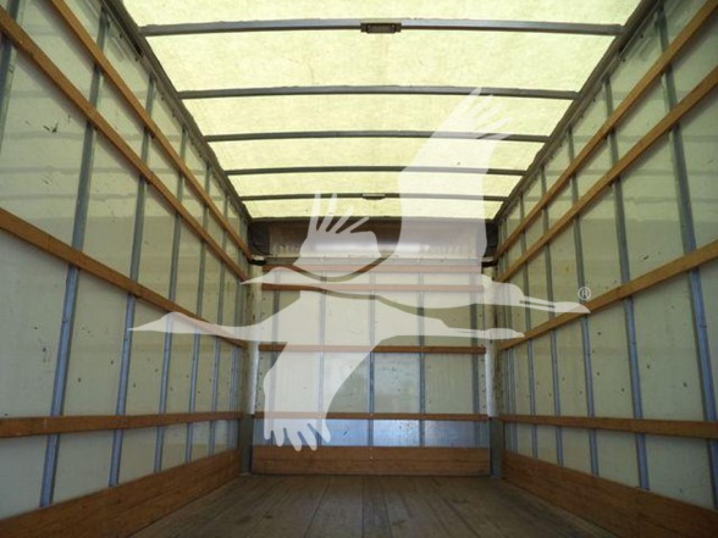 Trailer interior showing empty cargo area with wooden floor ribs and metal panel walls in a Ford E-Series box truck.