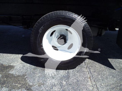 Front wheel and tire of a Ford E450 box truck with partial view of undercarriage and asphalt.