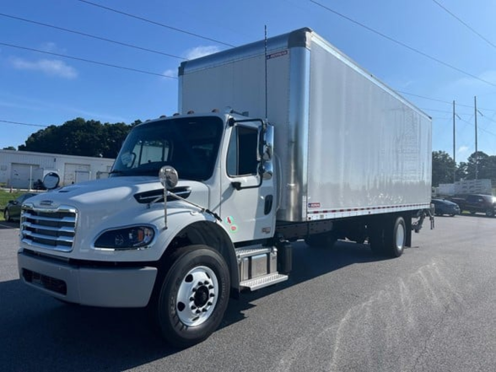 Box truck in view showing Freightliner M2-106 Plus with large box cargo area and white cab.