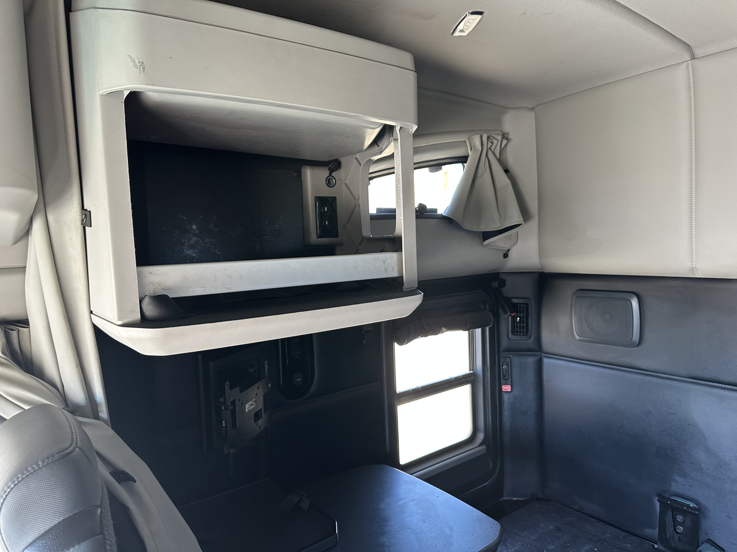 Kenworth T680 cab interior showing overhead storage with a mounted screen, window, and companion seating areas