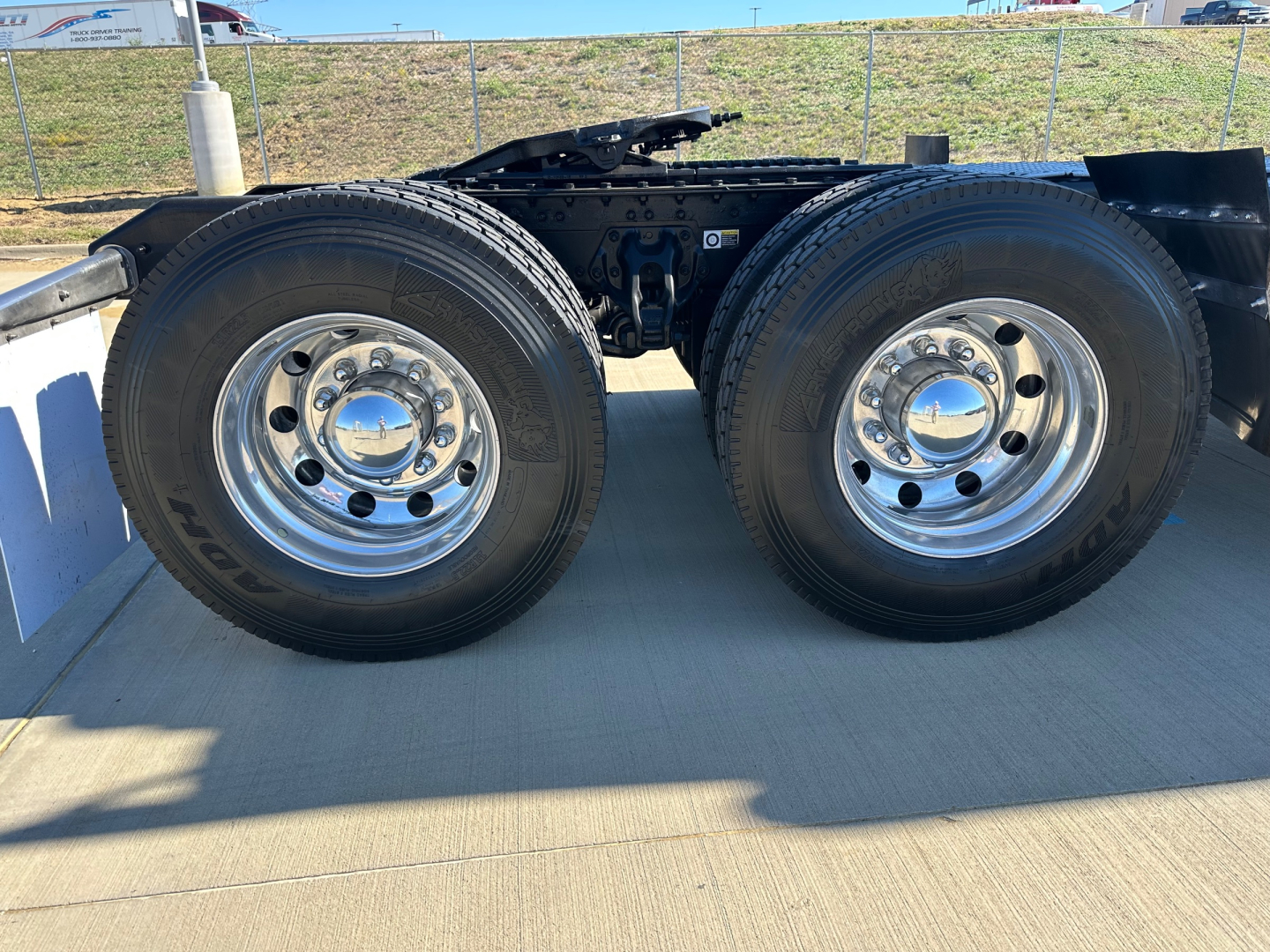 Kenworth T680 chassis with dual rear axles and chrome wheels, on a trailer. Side view shows tires and frame, no cargo bed visible.