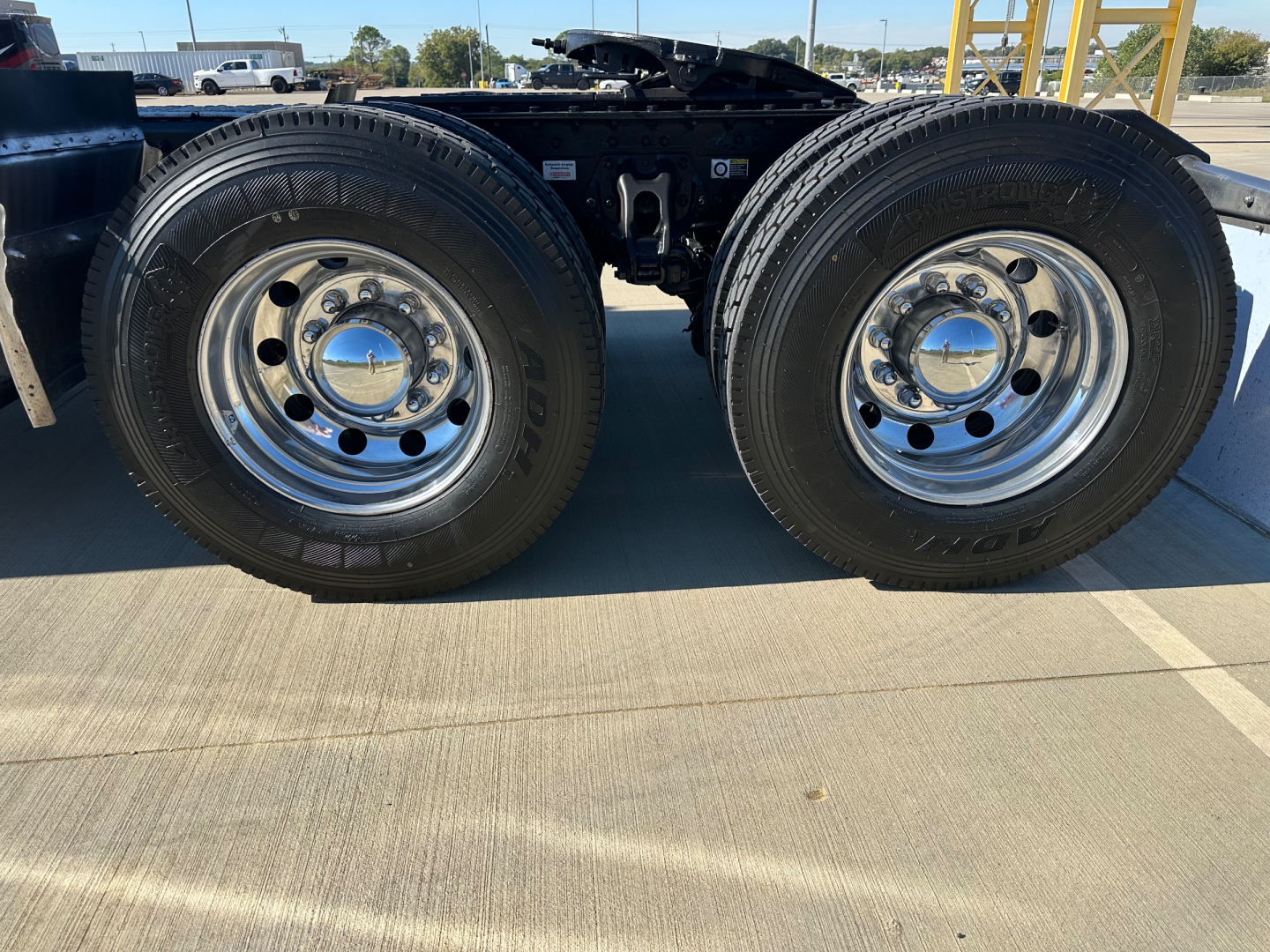 Kenworth T680 chassis with dual rear axles showing chrome wheels and tires, side view of the wheels and suspension undercarriage.