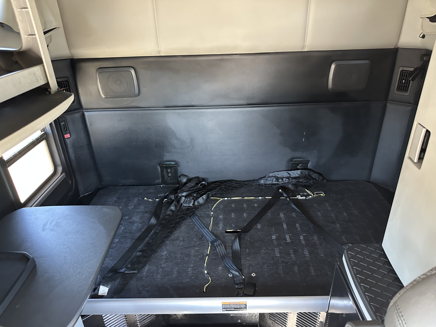 Kenworth T680 sleeper cab interior cargo area with seat belts, dark flooring, and side panels visible.