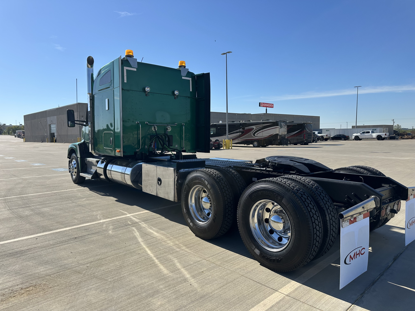 Kenworth T680 tractor chassis rear and cab side view with dual rear axles and sleeper, green cab, white mudflaps, chrome wheels.