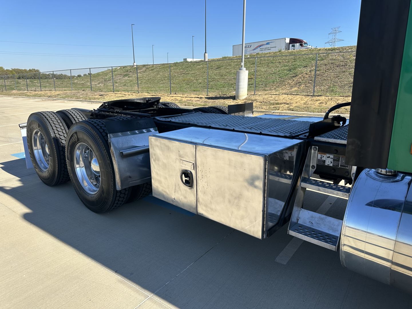Kenworth T680 truck side view showing chrome fuel/air tanks and toolbox along the frame, with dual rear axles and wheels.