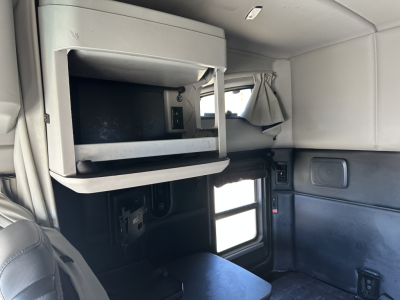 Kenworth T680 cab interior showing overhead storage with a mounted screen, window, and companion seating areas