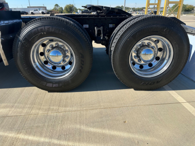 Kenworth T680 chassis with dual rear axles showing chrome wheels and tires, side view of the wheels and suspension undercarriage.