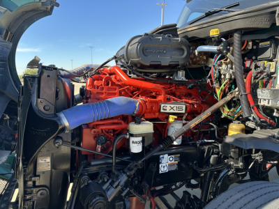 Kenworth T680 engine bay showing red engine block with blue coolant hose and various wiring harnesses.
