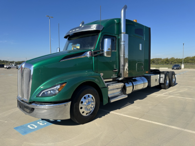 Kenworth T680 with green cab, sleeper, chrome exhaust stacks, and front chrome bumper parked in a lot.