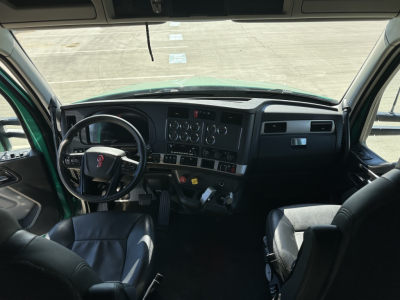 Truck cab interior showing steering wheel, dashboard, and driver seat from Kenworth T680; visible gauges and controls on the center stack.