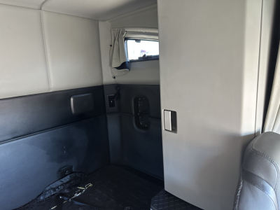 Kenworth T680 sleeper cab interior with side wall panel, window, and door latch visible in the cab area.