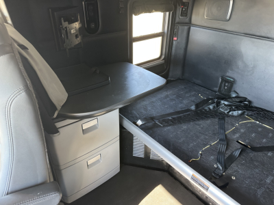 Kenworth T680 cab interior showing sleeper bunk area and storage drawers with flat desk surface.
