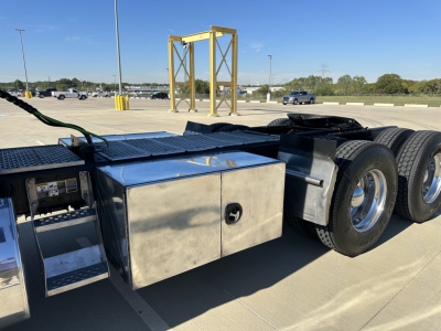 Kenworth T680 truck chassis showing aluminum tool/storage box and dual rear axles with wheels.