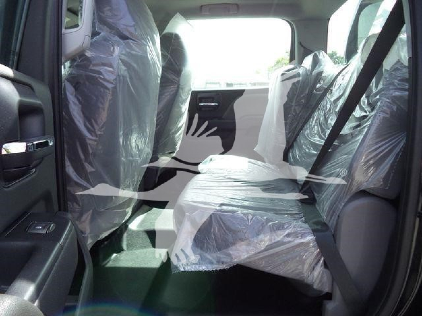 Interior of a new 2023 International CV truck showing plastic-wrapped seats and bench seating in the back, with rear passenger area visible.