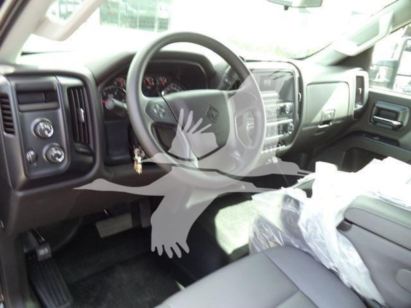 Interior of a new 2023 International CV truck showing steering wheel, dashboard, driver seat, and plastic-covered passenger seat.