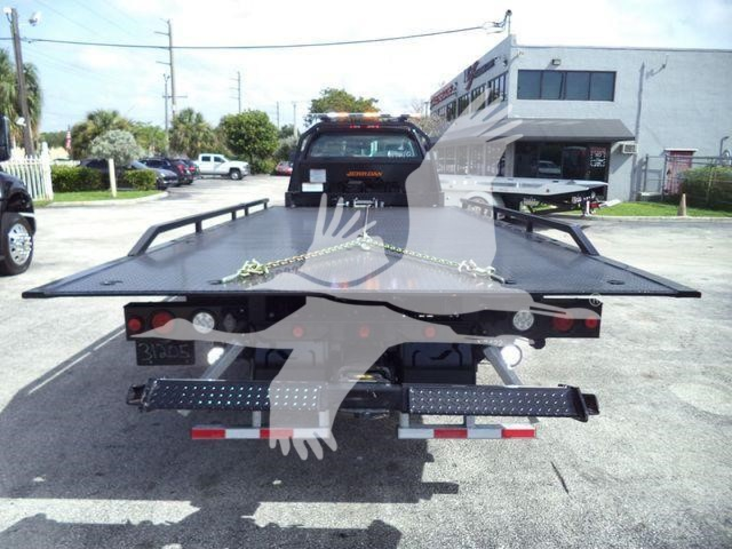 Tractor/fleet rollback truck bed seen from rear, with flatbed and rear lights, in a dealership lot.