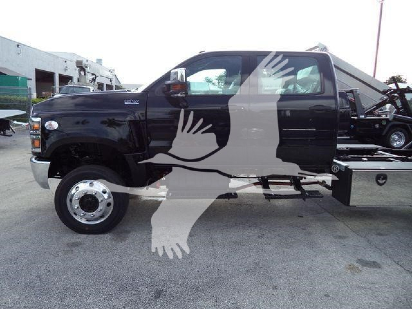 Truck side view showing 2023 International CV with rollback equipment and logos overlay