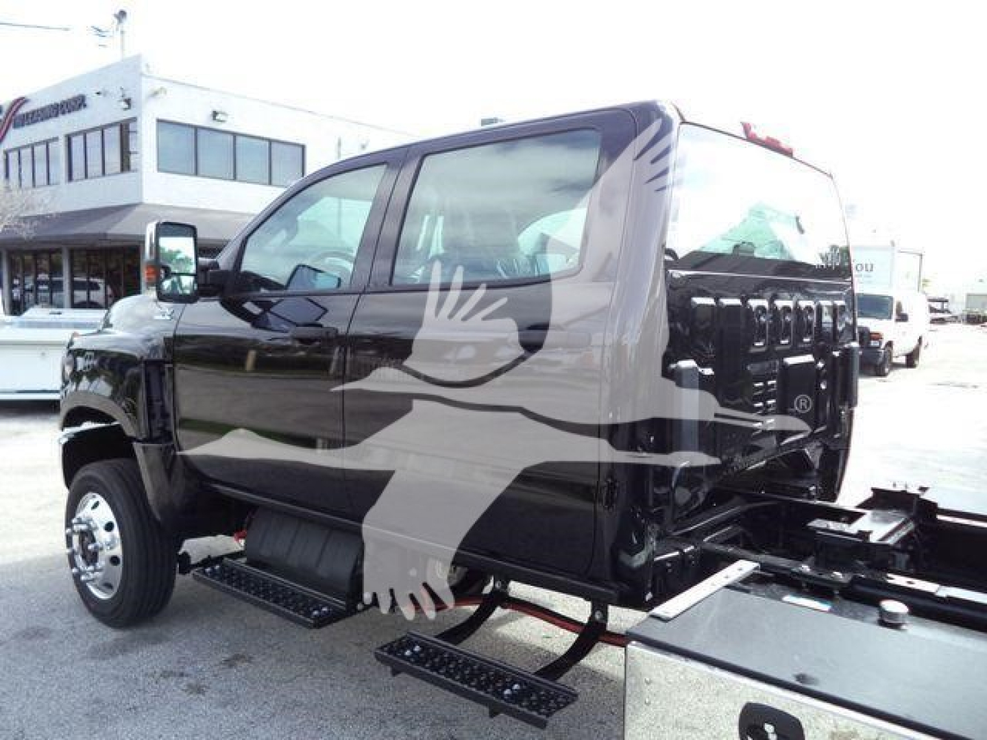 Tractor-trailer truck cab in black showing side steps and rollback equipment, with windows and front wheel visible.