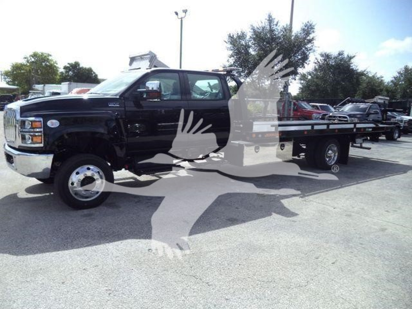 Tow truck/rollback truck on lot showing metal flatbed and black cab with chrome front, no visible text.