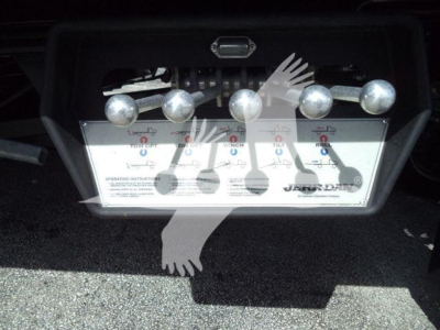 Control panel with multiple levers and an instruction diagram beneath, showing labels and symbols for operating a rollback truck attachment.