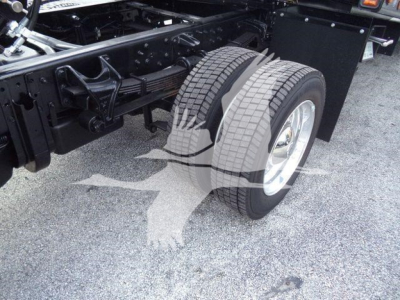 Truck chassis with dual rear wheels showing treaded tires and suspension components.
