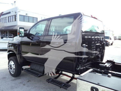 Tractor-trailer truck cab in black showing side steps and rollback equipment, with windows and front wheel visible.