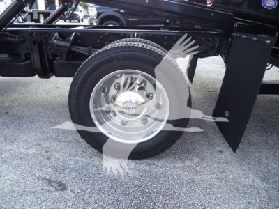 Wheel and part of truck chassis with a polished steel rim and tire; sticker or badge on hubcap visible.