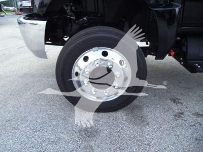 Truck front wheel with chrome hubcap and black tire; partial view of suspension and fender, watermark overlay.