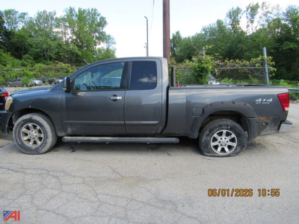 Nissan Titan pickup truck in side profile view showing extended cab, gray body, 4x4 badge, and running boards.