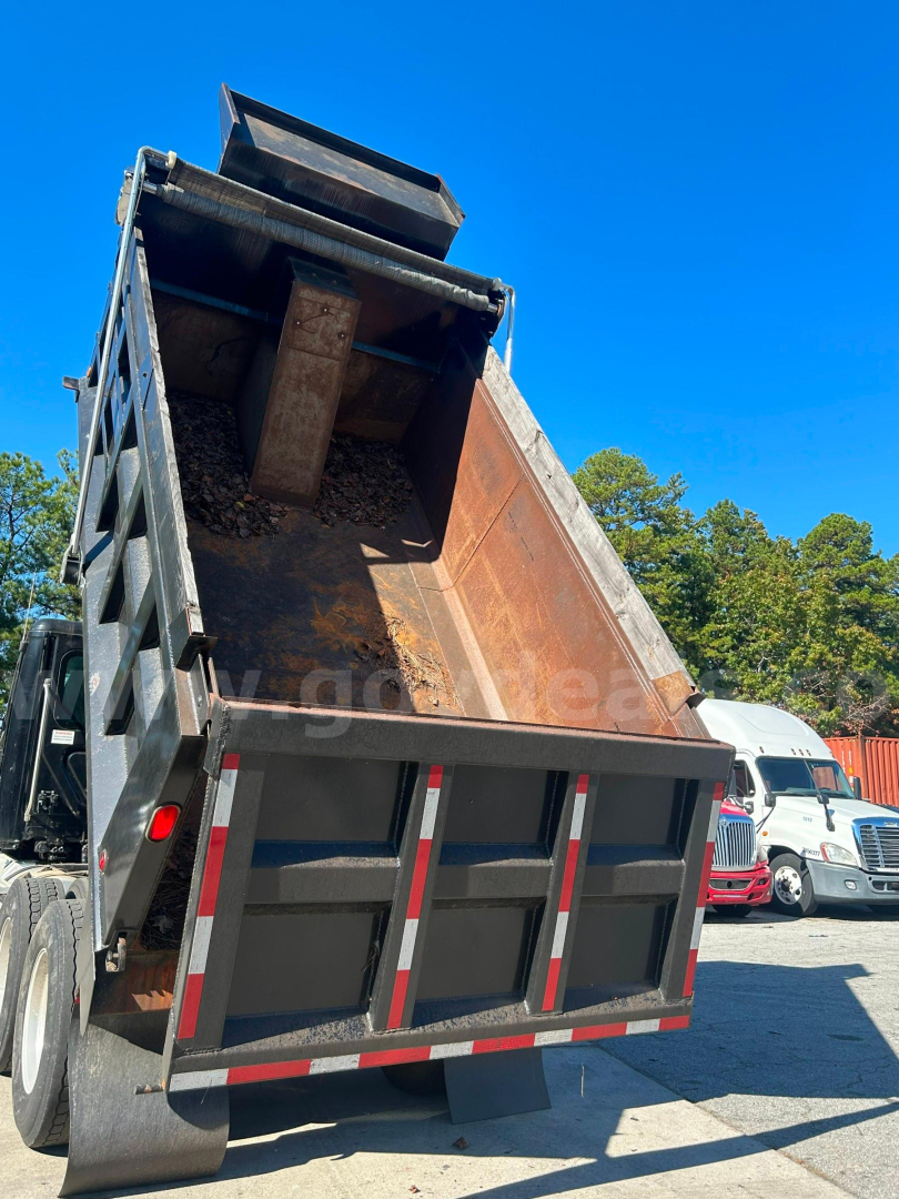 Dump truck bed showing raised tailgate and rusty cargo bed interior