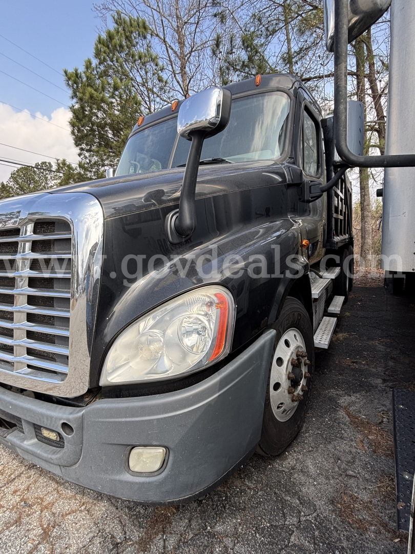 Truck front-left view of 2018 Freightliner Cascadia 125 dump truck showing solid front bumper, large grille, headlight, and side mirror.