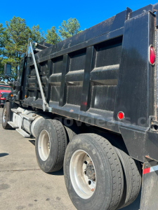 Dump truck rear view showing Freightliner Cascadia dump bed with dual rear axles and black paint.