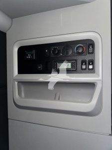 Cab panel of a 2023 Kenworth T680 sleeper truck showing dashboard controls and storage pocket.