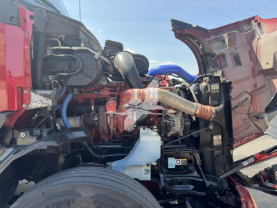 Kenworth T680 engine bay with open hood and visible components such as air intake, turbo, hoses, coolant reservoir, and engine block.
