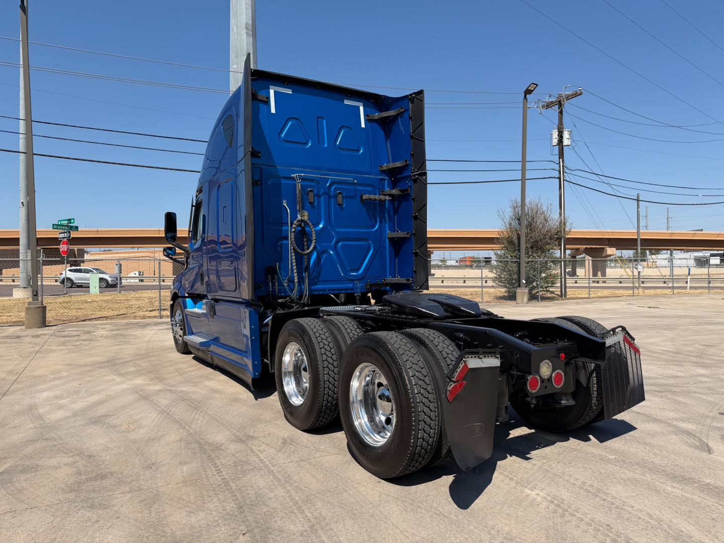 Truck cab rear and chassis of a blue Freightliner PT126064ST tractor showing dual rear axles, mud flaps, and fifth-wheel area.