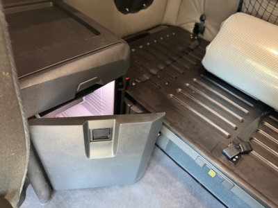 Freightliner PT126064ST sleeper cab interior showing storage drawer and seating area with ribbed floor and a plastic storage bin.