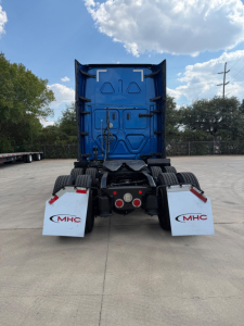 Freightliner truck rear view showing blue sleeper cab and dual rear wheels with white mudflaps labeled MHC.