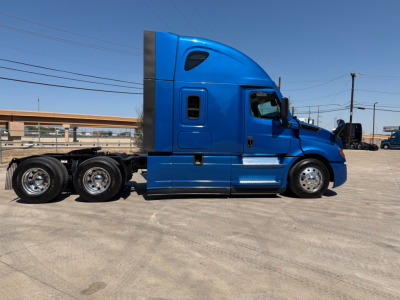 Blue Freightliner PT126064ST conventional sleeper tractor side view showing cab, chrome steps, dual rear axles, and fuel tanks.